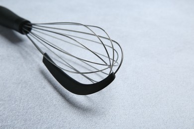 Photo of Metal whisk on gray table, closeup. Space for text