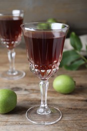 Photo of Delicious liqueur and green walnuts on wooden table