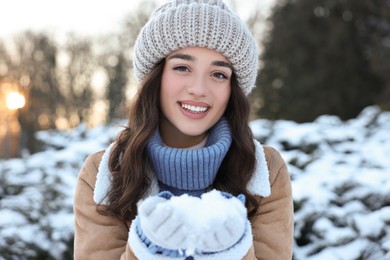 Photo of Portrait of smiling woman holding pile of snow in park