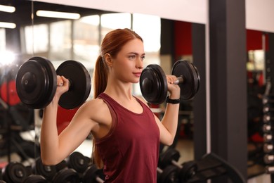 Athletic young woman with barbell training in gym