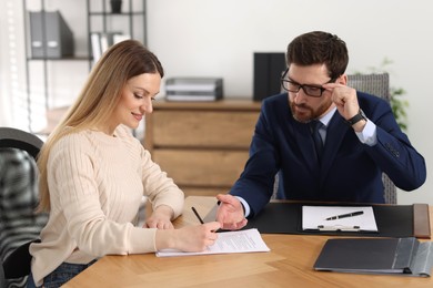 Photo of Woman signing document while having meeting with lawyer in office