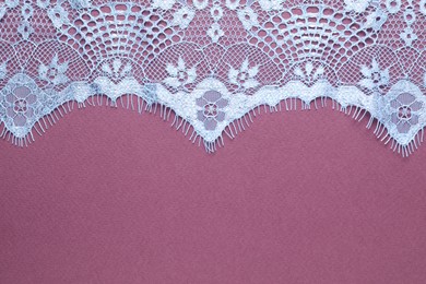 Photo of White lace on purple background, top view. Space for text