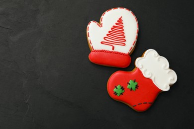 Photo of Mitten and stocking shaped Christmas cookies on black table, flat lay. Space for text