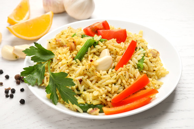 Tasty rice pilaf with vegetables on white wooden table, closeup