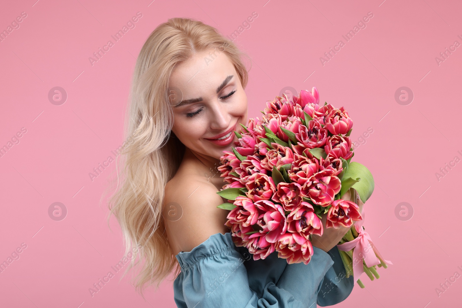 Photo of Happy young woman with beautiful bouquet on dusty pink background