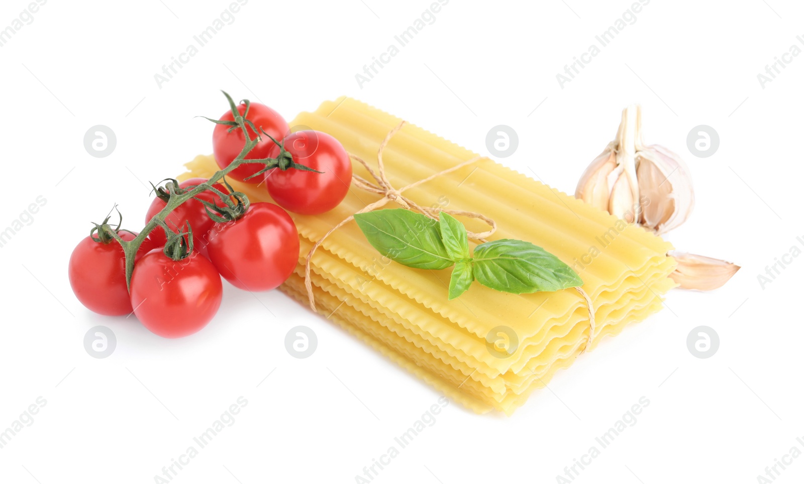 Photo of Uncooked lasagna sheets with cherry tomatoes, garlic and basil isolated on white