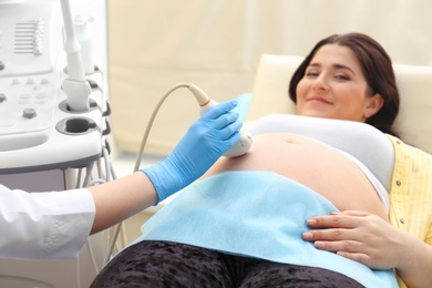 Photo of Young pregnant woman undergoing ultrasound scan in clinic