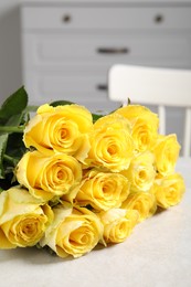 Beautiful bouquet of yellow roses on light grey table indoors