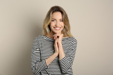 Portrait of happy young woman with beautiful blonde hair and charming smile on beige background