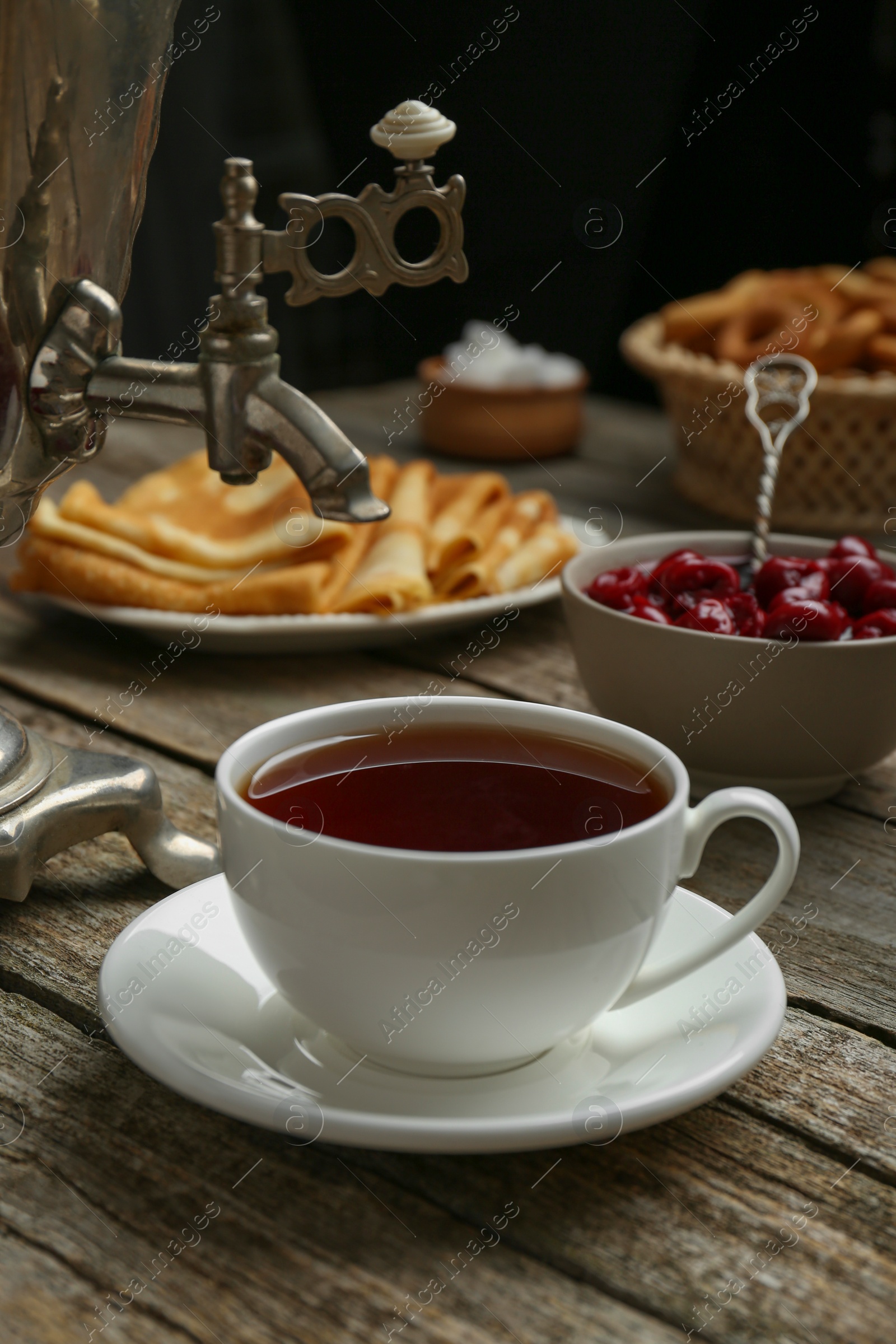 Photo of Metal samovar with cup of tea and treats on wooden table