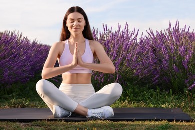 Photo of Woman practicing yoga near lavender outdoors. Space for text