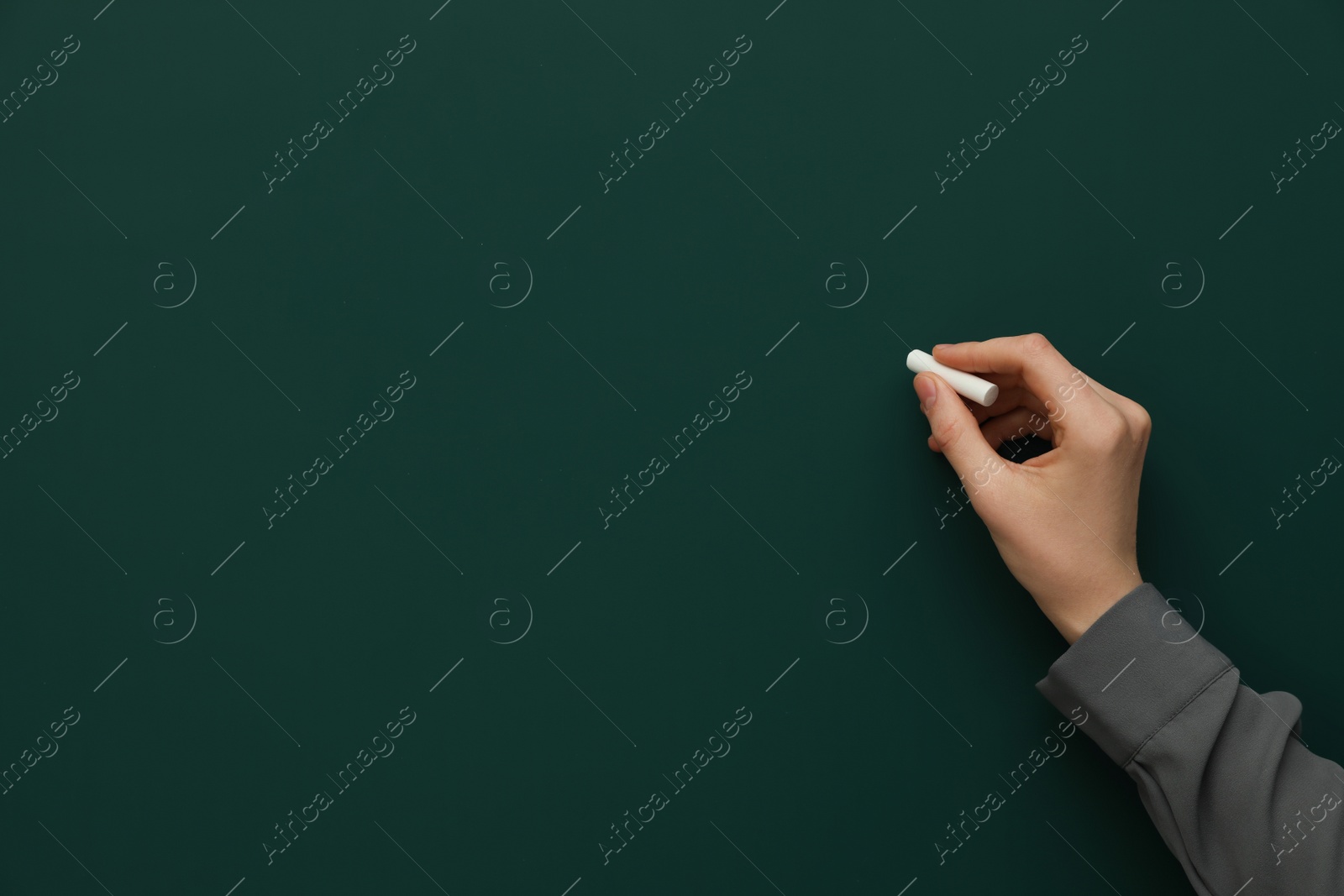 Photo of Woman with white chalk near green board, closeup. Space for text