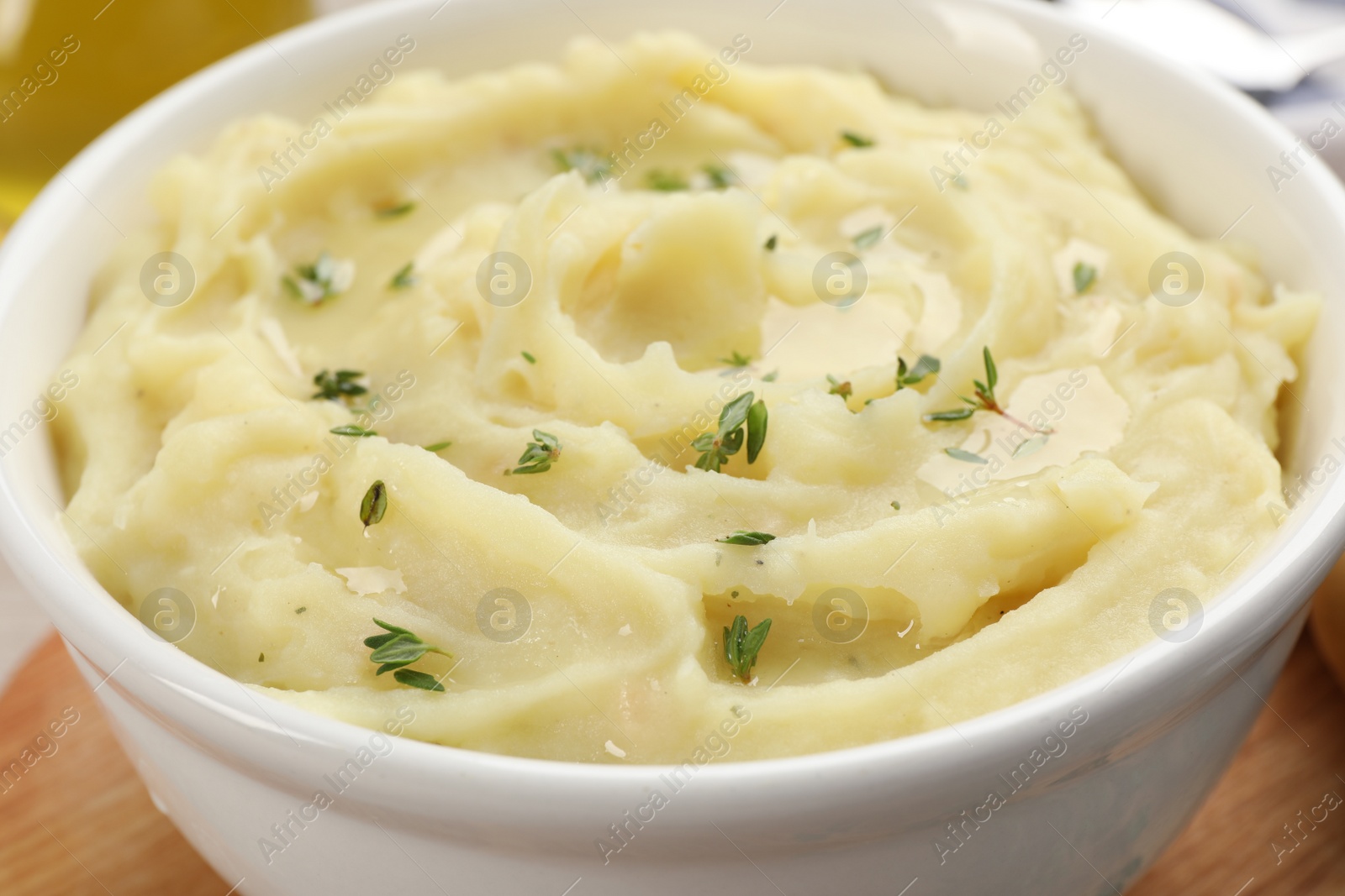 Photo of Bowl of tasty mashed potato with rosemary on wooden table, closeup