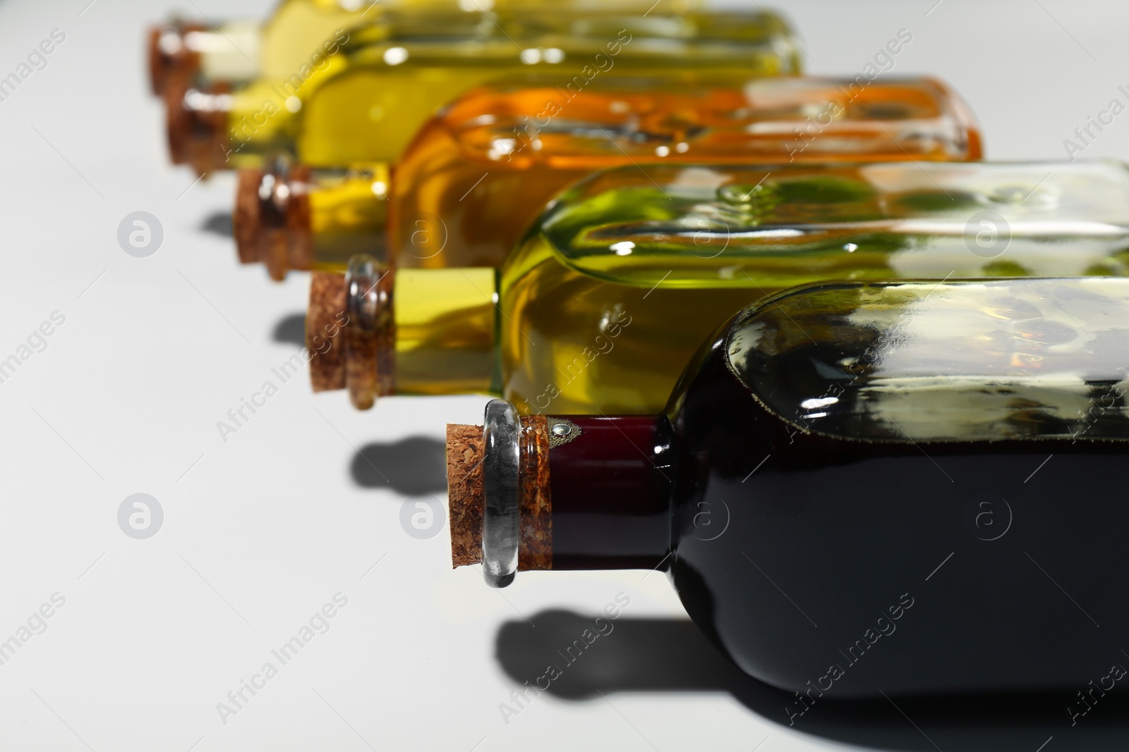 Photo of Vegetable fats. Different cooking oils in glass bottles on white background, closeup. Space for text