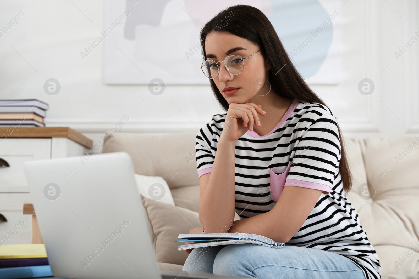 Photo of Young woman watching webinar on sofa at home