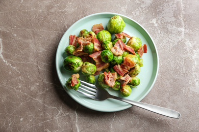 Delicious Brussels sprouts with bacon on marble table, top view