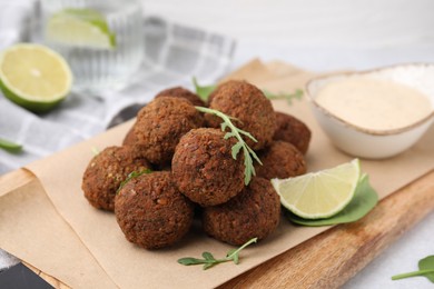 Delicious falafel balls, arugula, lime and sauce on table