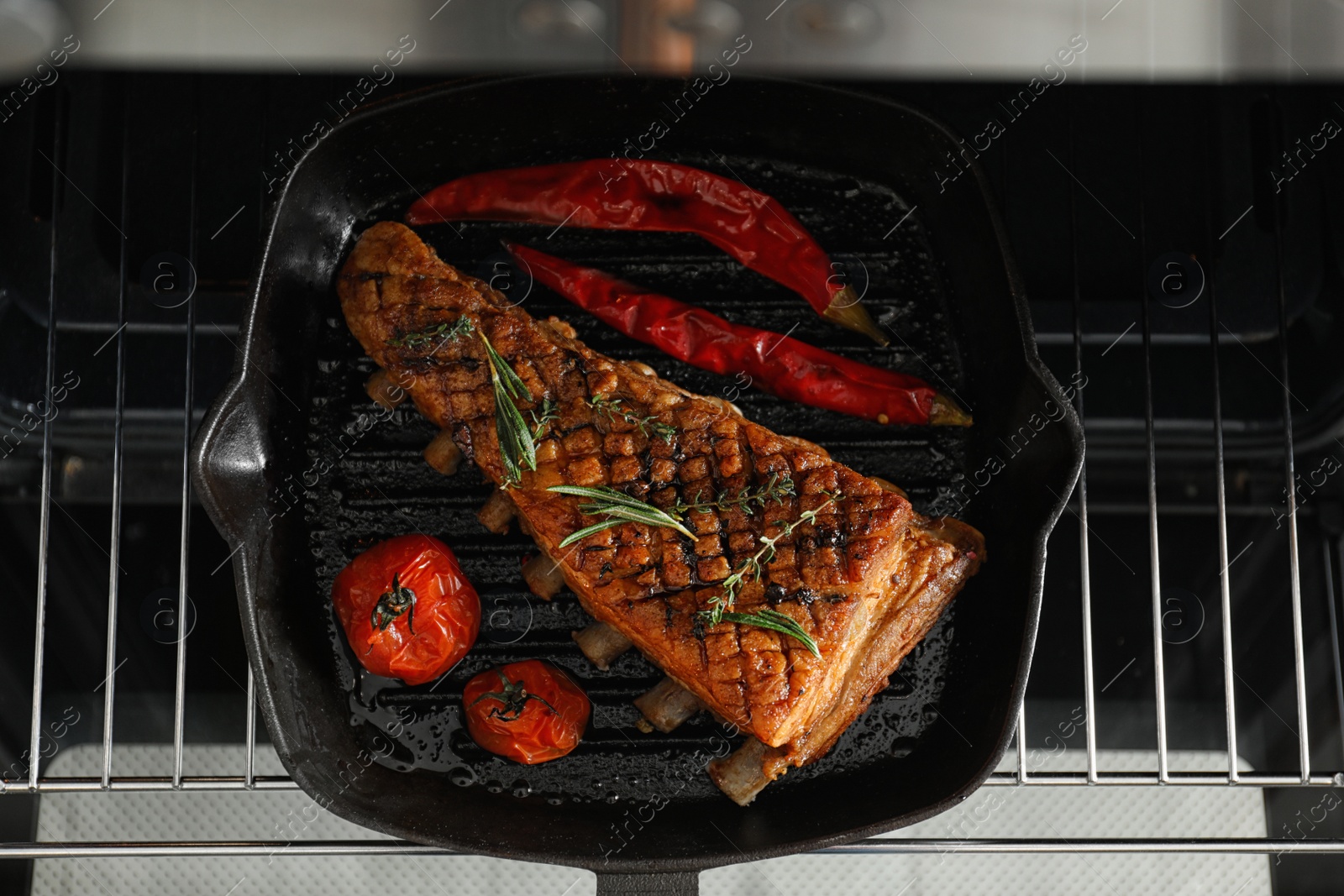 Photo of Delicious roasted ribs on pan in oven, top view