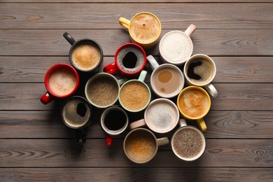 Many different cups with aromatic coffee on wooden table, flat lay