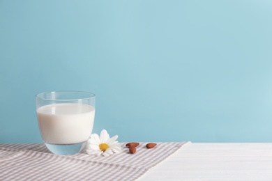 Glass of milk on table against color wall