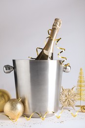 Photo of Happy New Year! Bottle of sparkling wine in bucket and festive decor on white background