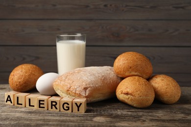 Image of Food allergy. Bread, milk, egg and cubes on wooden table