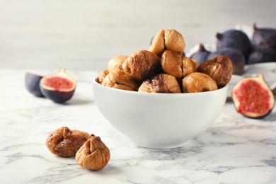 Photo of Bowl with delicious dried figs on marble table. Organic snack