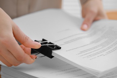 Woman attaching documents with metal binder clip, closeup