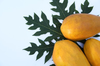 Fresh ripe papaya fruits and leaf on white background, flat lay. Space for text