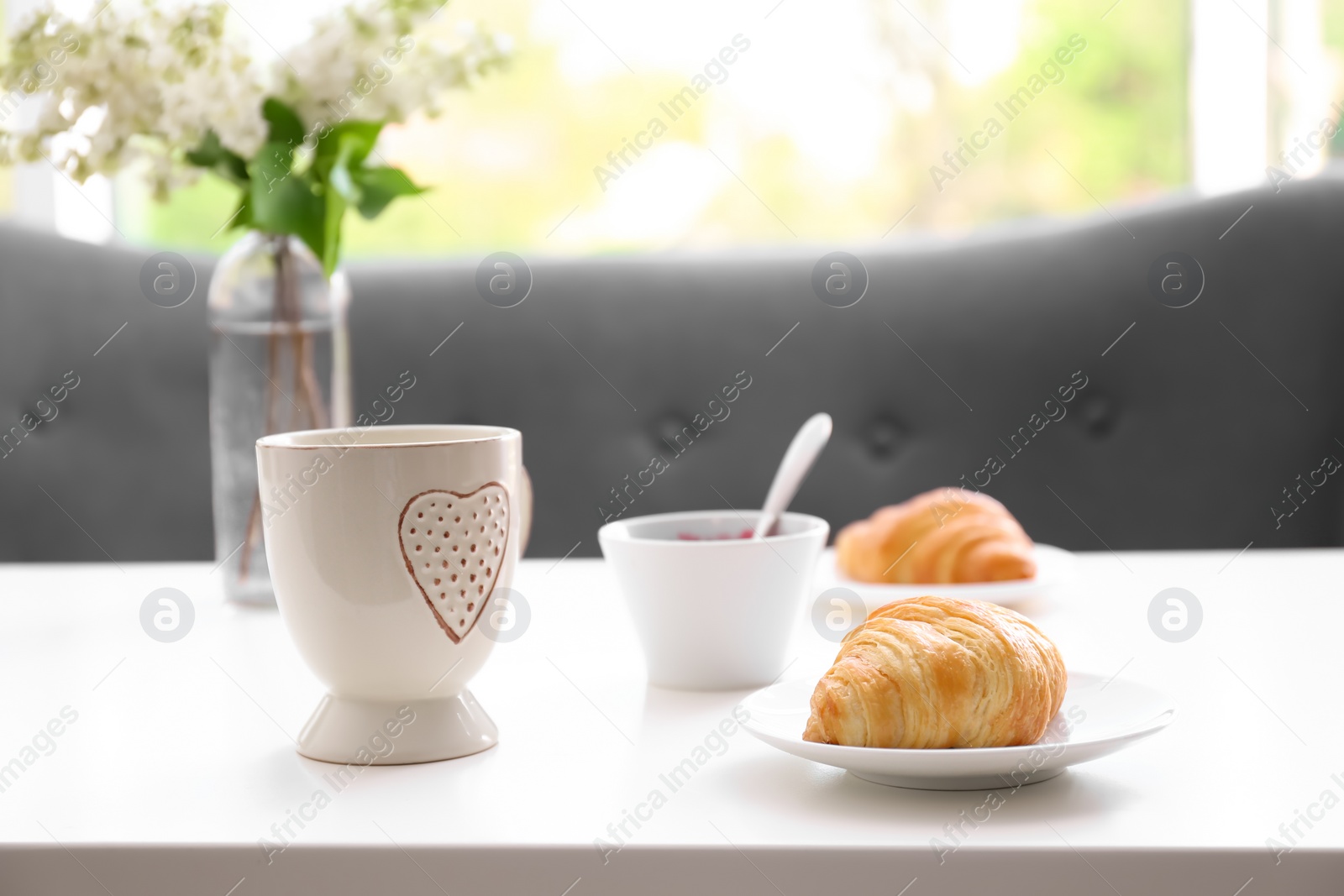 Photo of Cup and plate with tasty freshly baked croissant on table