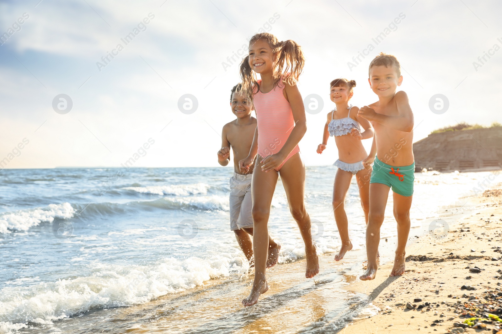 Photo of Cute children enjoying sunny day at beach. Summer camp