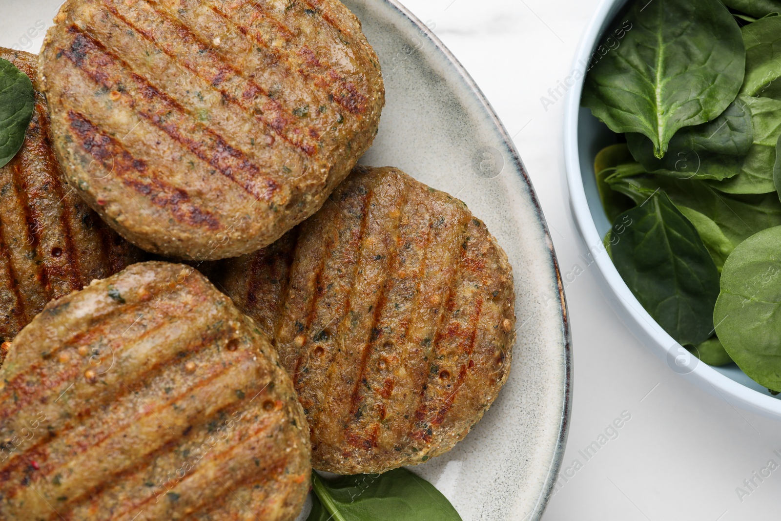 Photo of Tasty grilled vegan cutlets and spinach on white table, top view