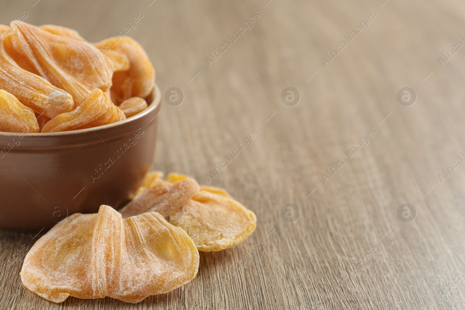 Photo of Delicious dried jackfruit slices on wooden table, closeup. Space for text