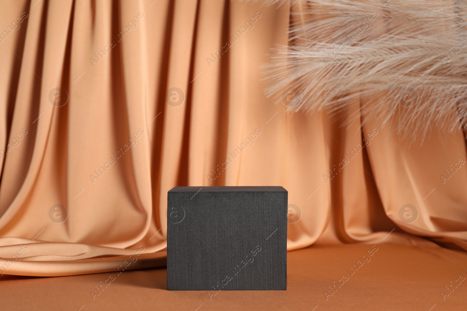 Photo of Black cube on light brown fabric, space for text. Stylish presentation for product