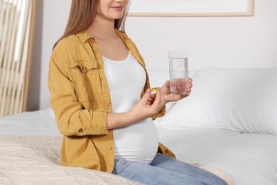 Photo of Pregnant woman taking pill at home, closeup. Space for text