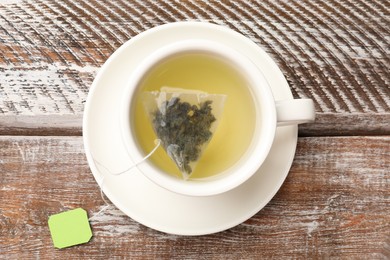 Photo of Tea bag in cup with hot drink on wooden rustic table, top view