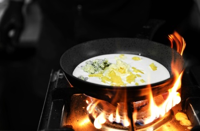 Photo of Frying pan with cheese and cream on stove