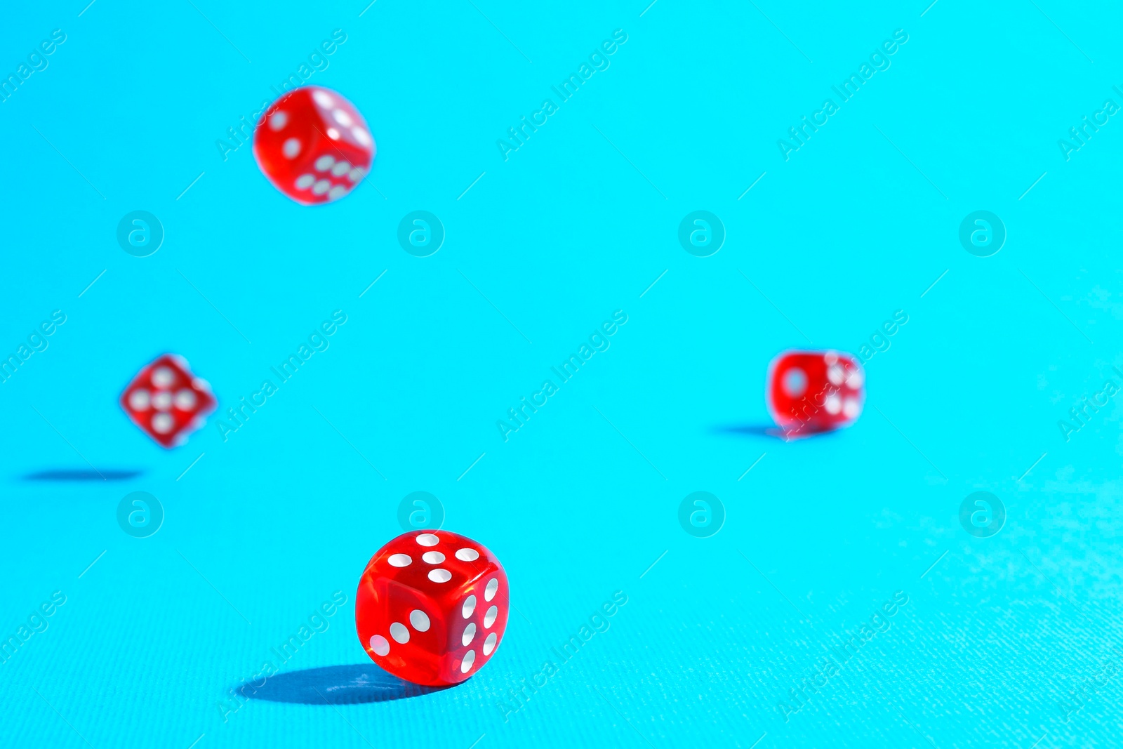 Photo of Many red game dices falling on light blue background