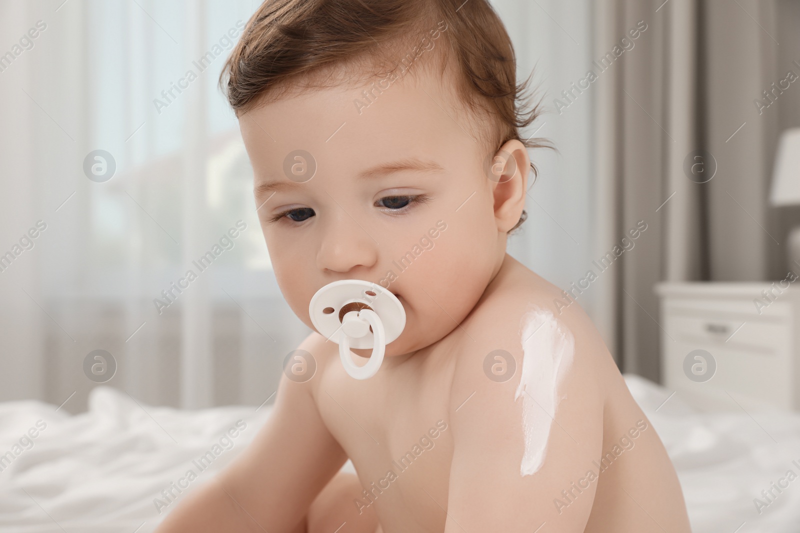 Photo of Cute little baby with cream on arm indoors