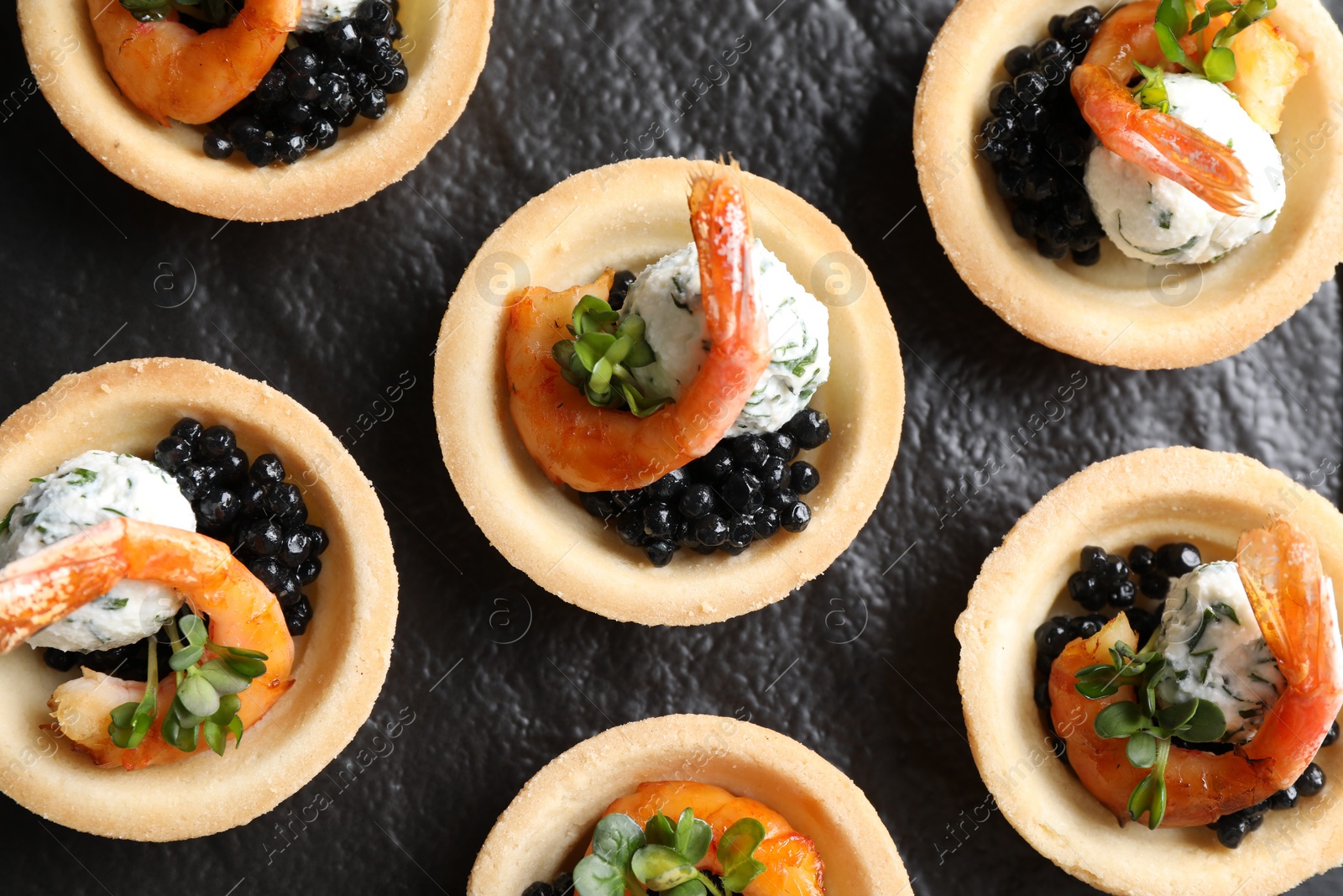 Photo of Delicious canapes with shrimps and black caviar on table, top view