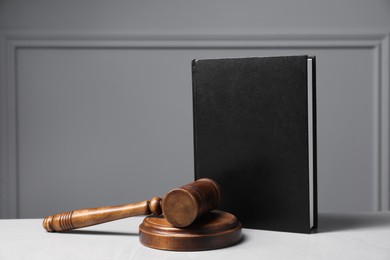 Photo of Law. Book, gavel and sound block on light table against gray background