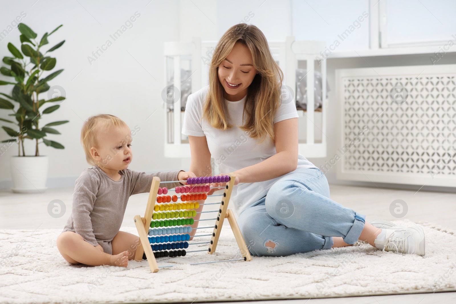 Photo of Children toys. Happy mother and her little son playing with wooden abacus on rug at home