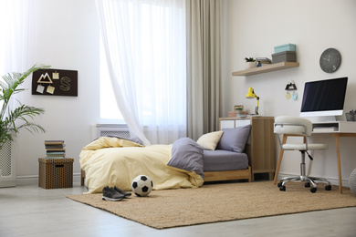 Stylish teenager's room interior with comfortable bed and workplace