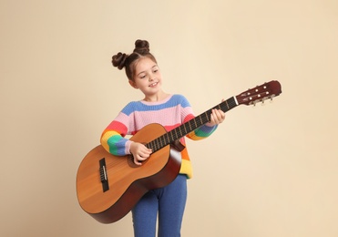 Photo of Cute little girl playing guitar on color background