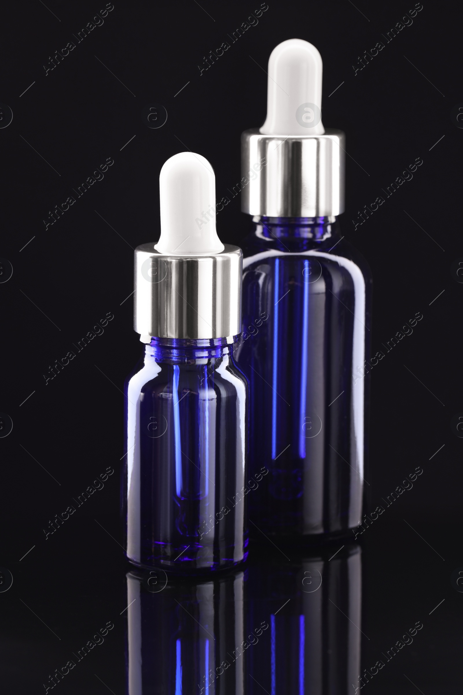 Photo of Tincture in bottles on mirror table against dark background