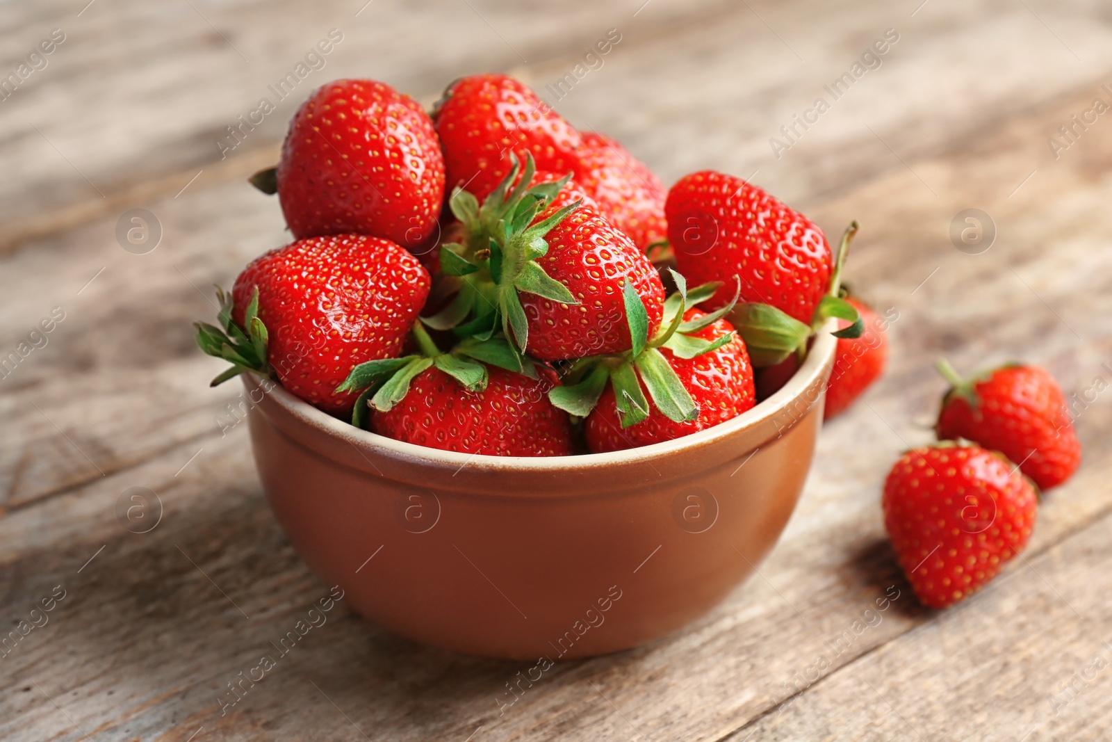 Photo of Bowl with ripe red strawberries on wooden table