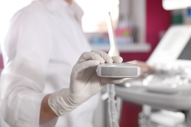 Photo of Sonographer holding ultrasound machine probe in clinic, closeup