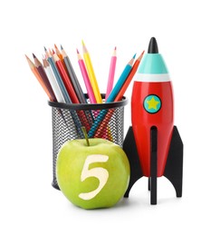 Apple with carved number five as school grade. Bright toy rocket and pencils on white background