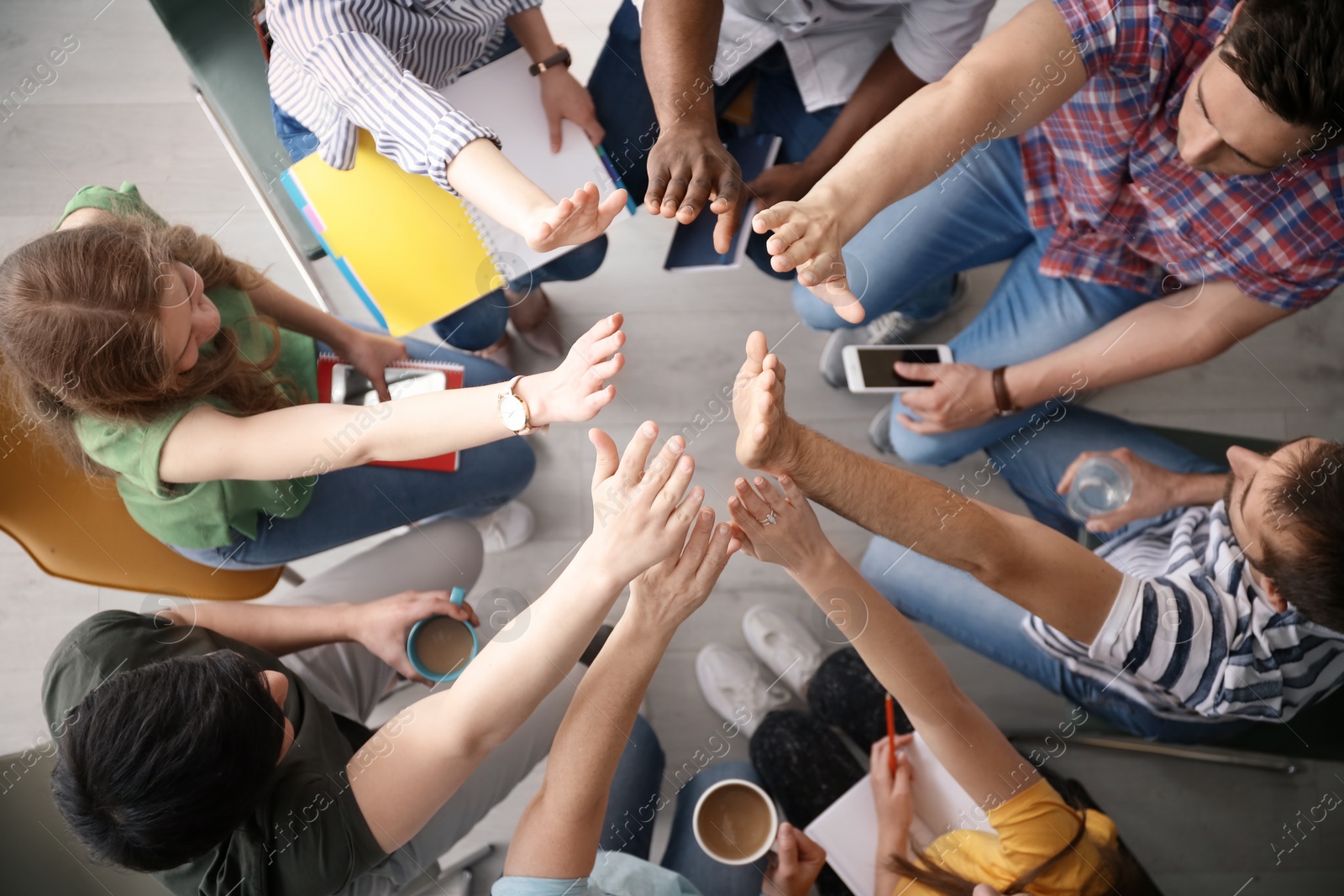 Photo of People putting hands together indoors, top view. Unity concept