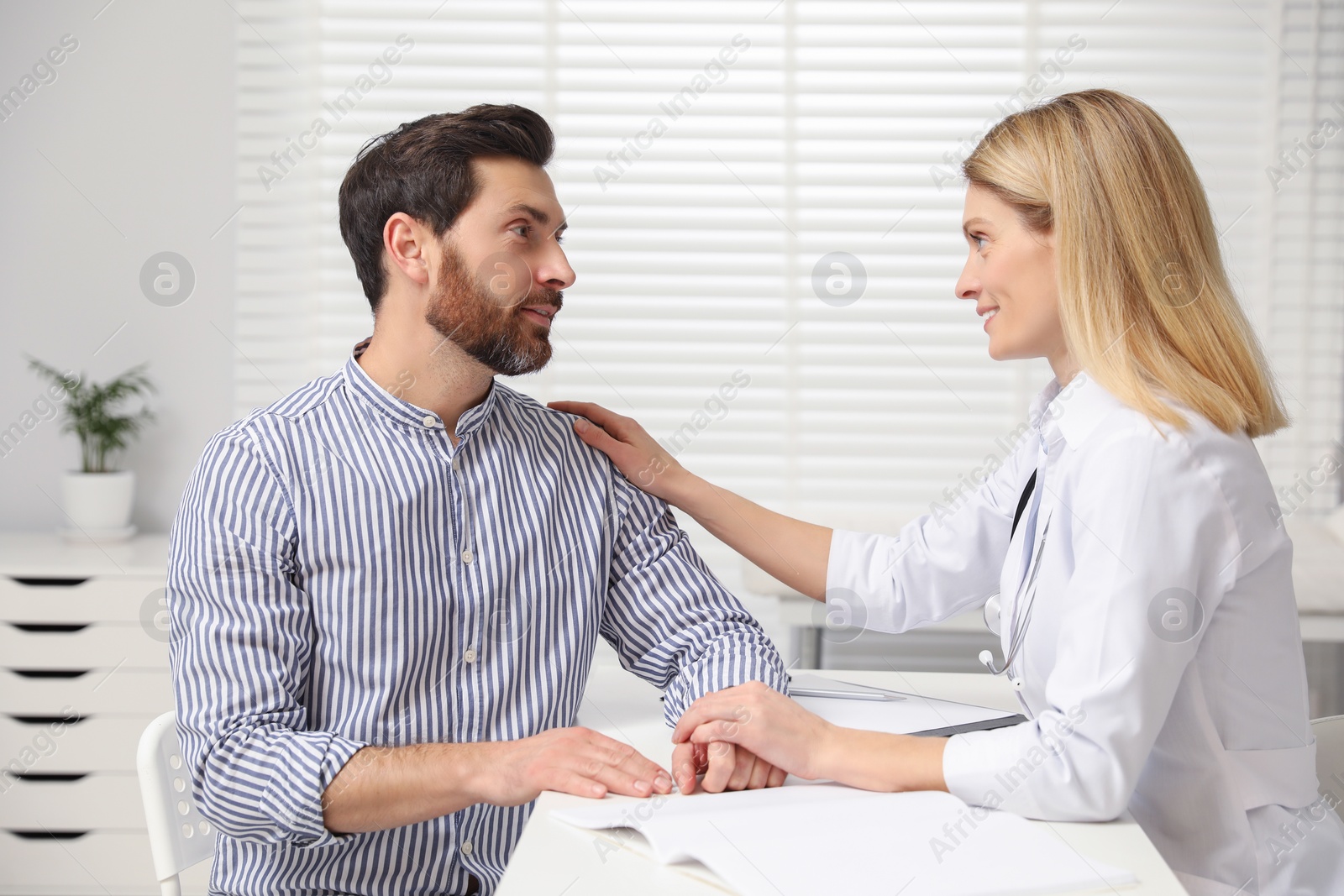 Photo of Doctor consulting patient at white table in clinic